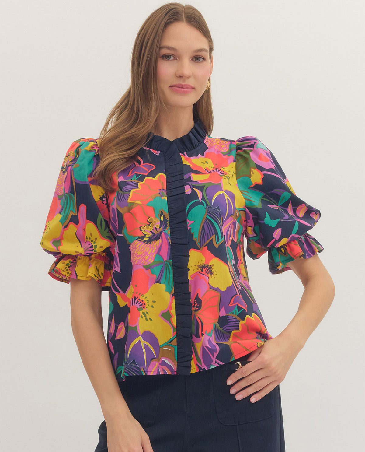 Woman wearing a colorful floral blouse against a plain background
