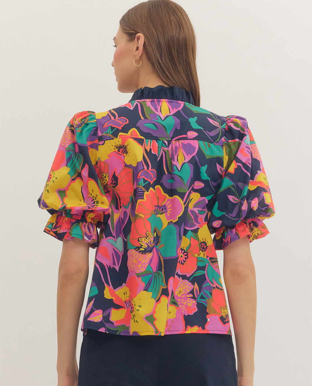 Woman wearing a colorful floral blouse with ruffled sleeves on a white background