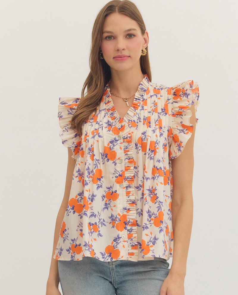 Woman wearing a floral blouse with orange and purple flowers on a plain background