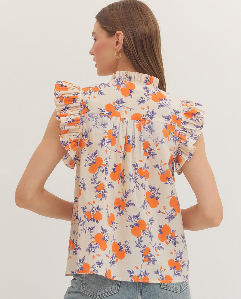 Woman wearing a floral blouse with orange and purple flowers on a plain background