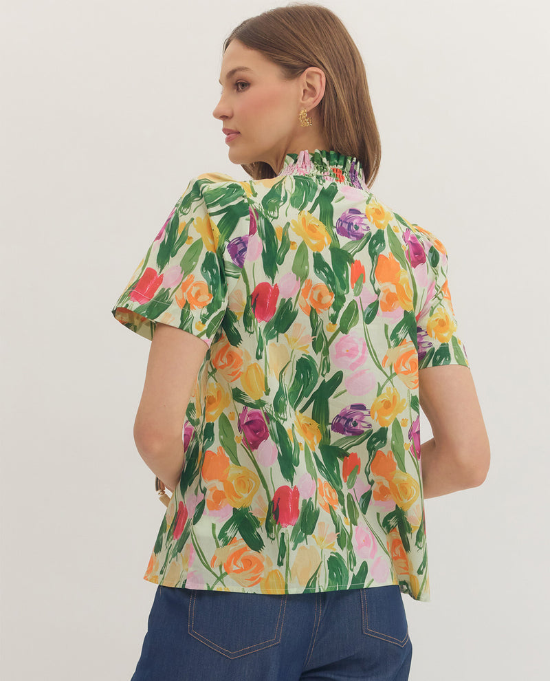 Woman wearing a colorful floral blouse against a plain background