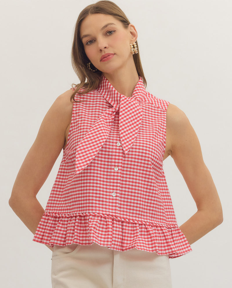 Woman wearing a red and white checkered blouse with a bow tie on a plain background