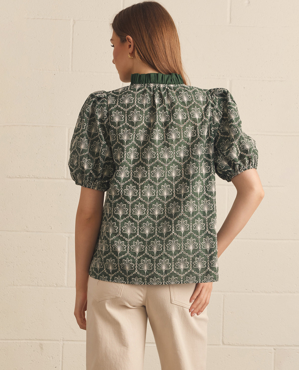 Woman wearing a patterned blouse with puff sleeves against a light background