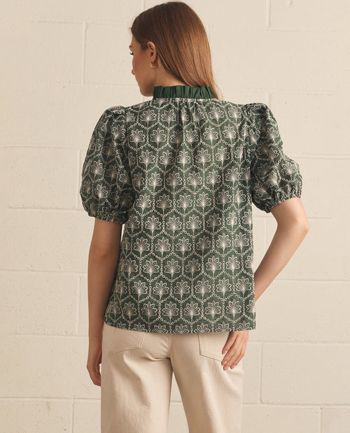 Woman wearing a patterned blouse with puff sleeves against a light background