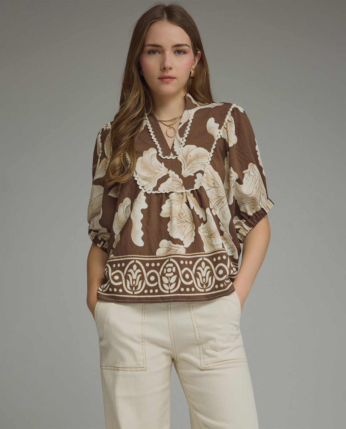 Woman wearing a brown floral blouse with a gray background