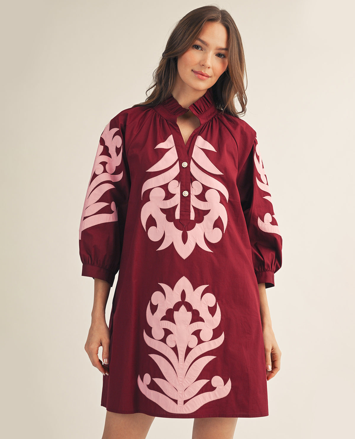 Woman wearing a burgundy dress with pink floral patterns on a beige background