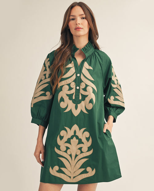 Woman wearing a green dress with beige floral patterns on a beige background
