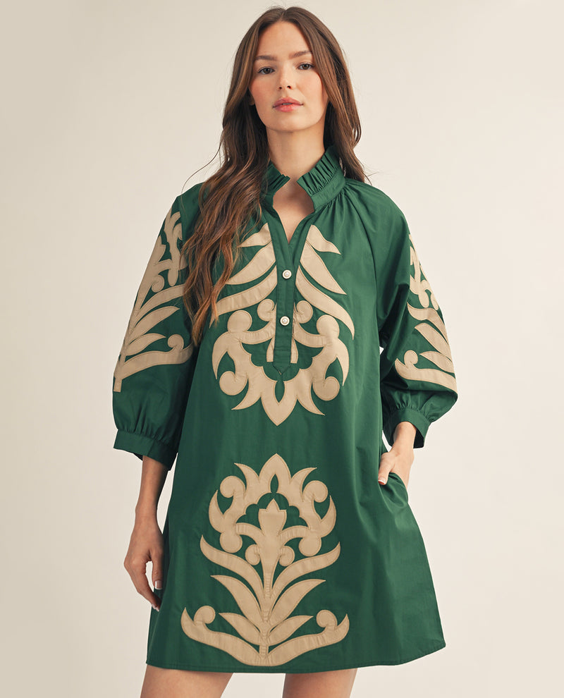 Woman wearing a green dress with beige floral patterns on a beige background