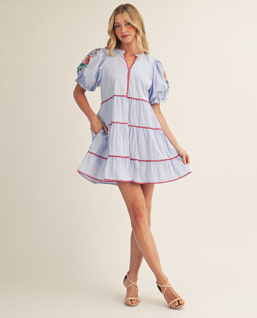 Woman wearing a light blue dress with red trim on a beige background