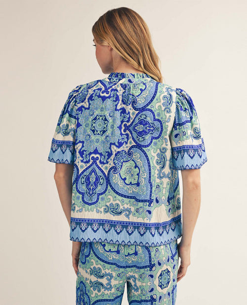 Person wearing a blue and white patterned outfit on a beige background