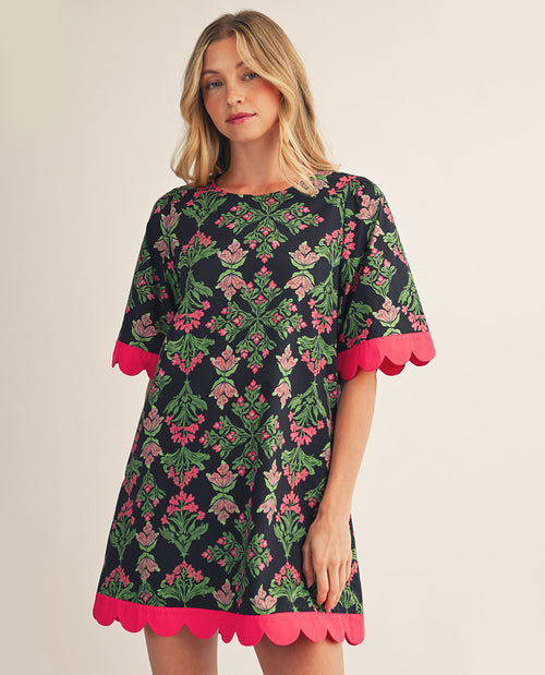 Woman wearing a floral dress with pink accents on a plain background