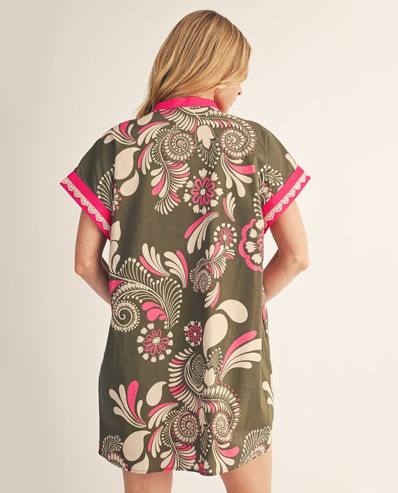 Woman wearing a floral patterned dress with pink accents on a plain background