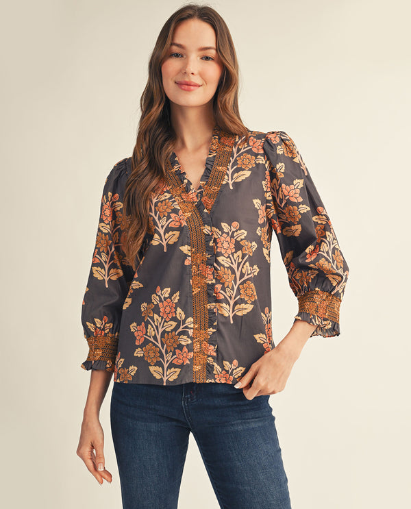 Woman wearing a floral blouse with long sleeves on a beige background