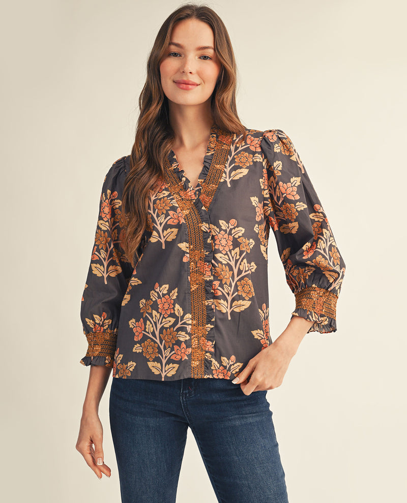 Woman wearing a floral blouse with long sleeves on a beige background