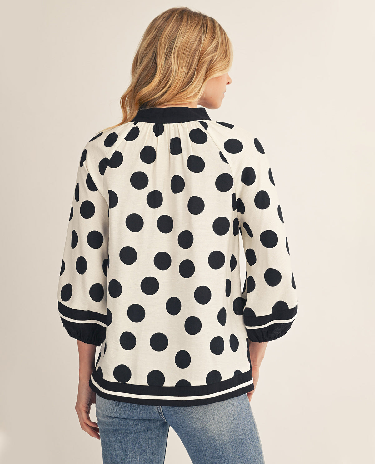 Woman wearing a polka dot blouse with a neutral background