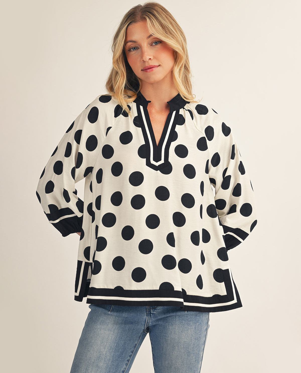 Woman wearing a black and white polka dot blouse with a plain background