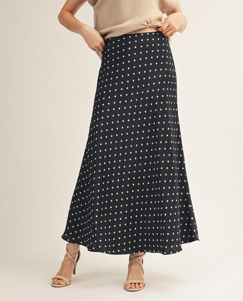 Person wearing a black polka dot skirt on a plain background