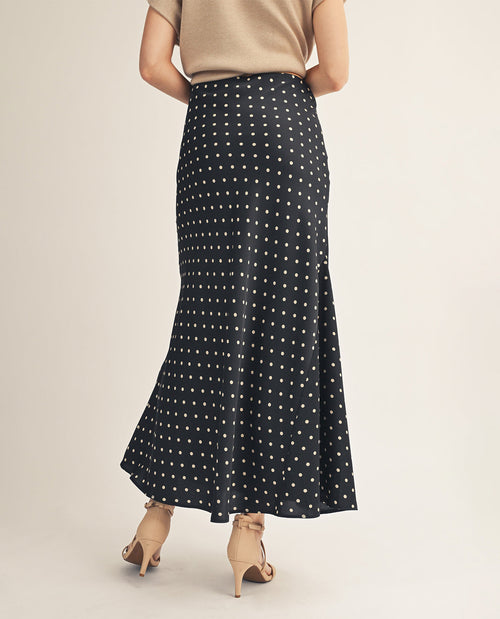 Person wearing a black polka dot skirt on a plain background