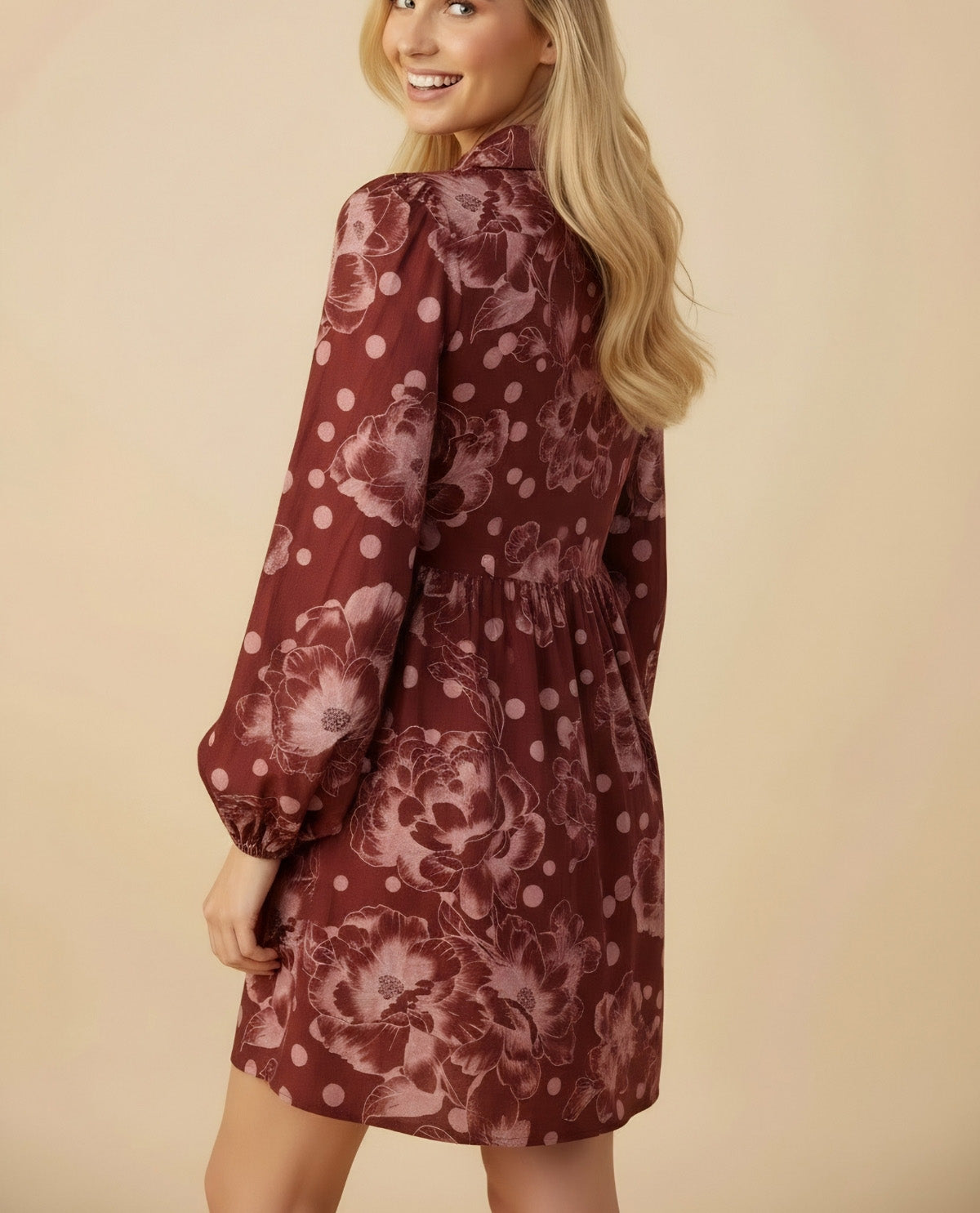 Woman wearing a burgundy floral dress against a beige background