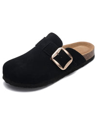 A black suede clog-style mule shoe with a large rectangular buckle strap, a tan cork-look footbed, and a black sole, shown on a plain white background.