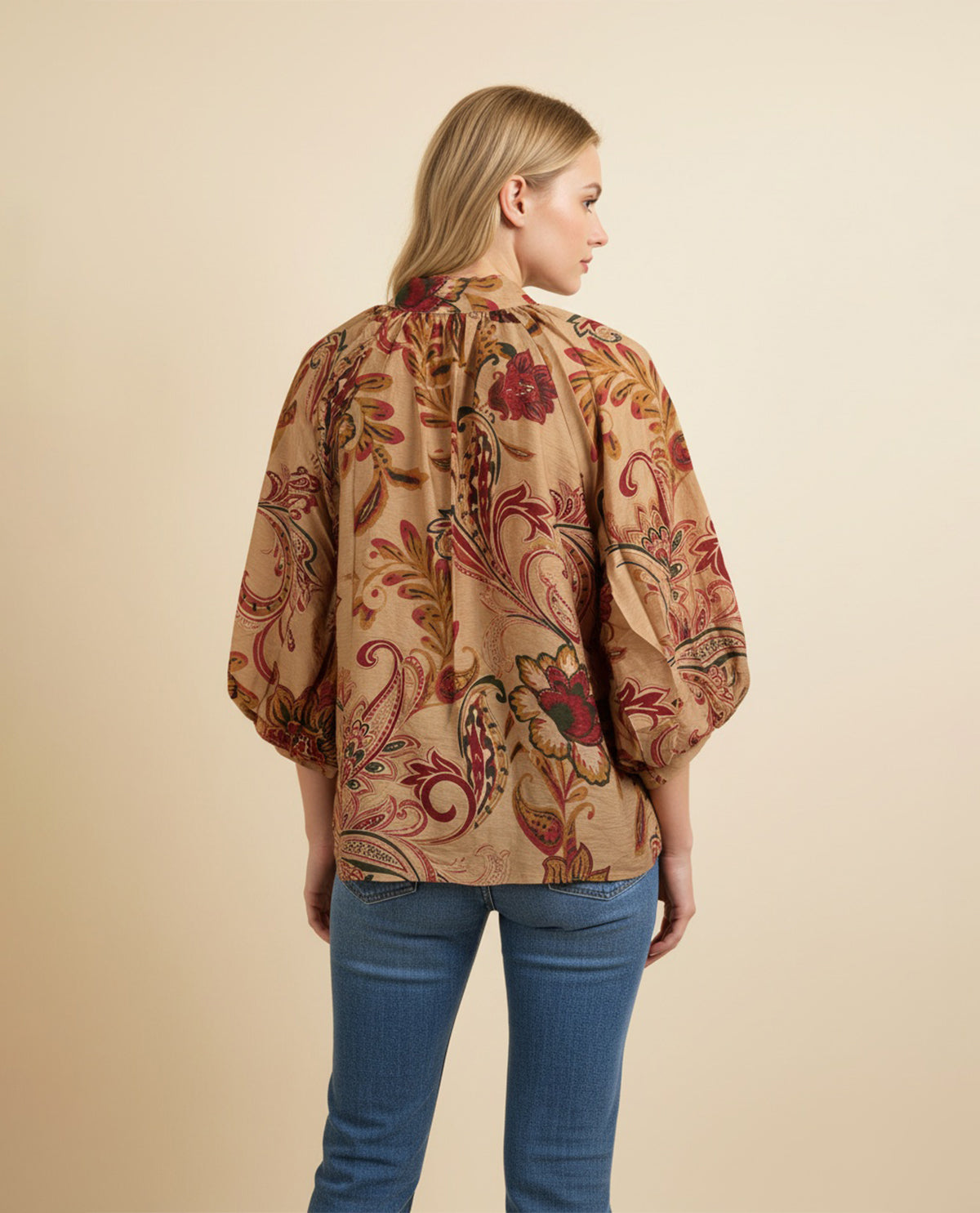 Woman wearing a patterned blouse with a beige background