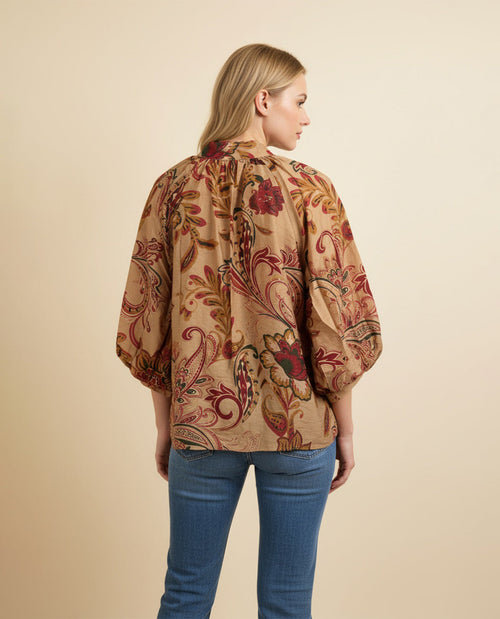 Woman wearing a patterned blouse with a beige background