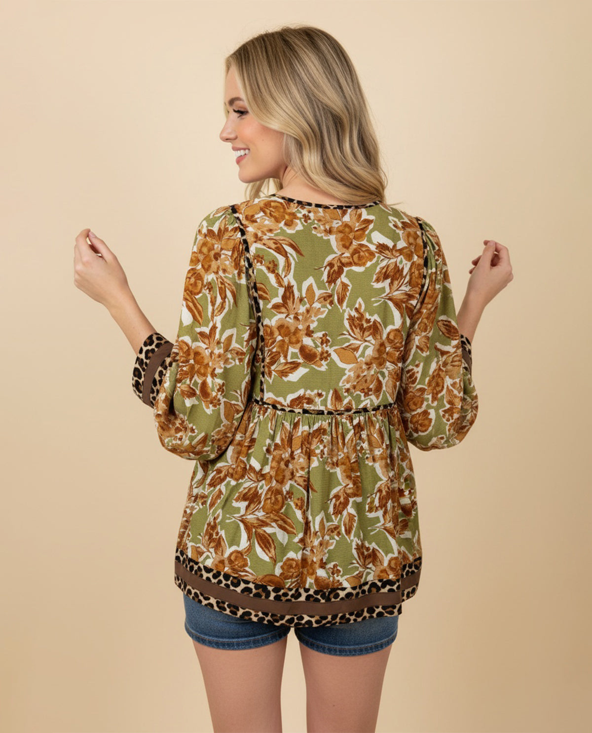 Woman wearing a floral and leopard print top against a beige background