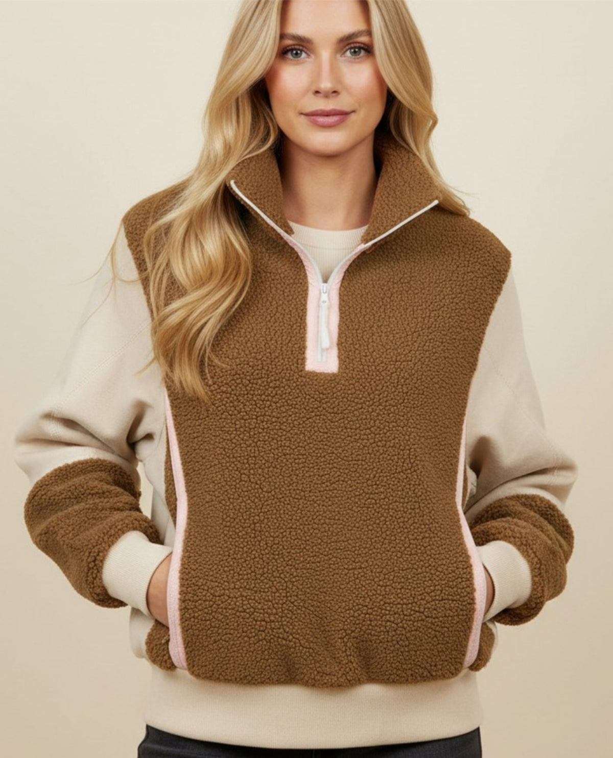 Woman wearing a brown and beige fleece pullover against a beige background