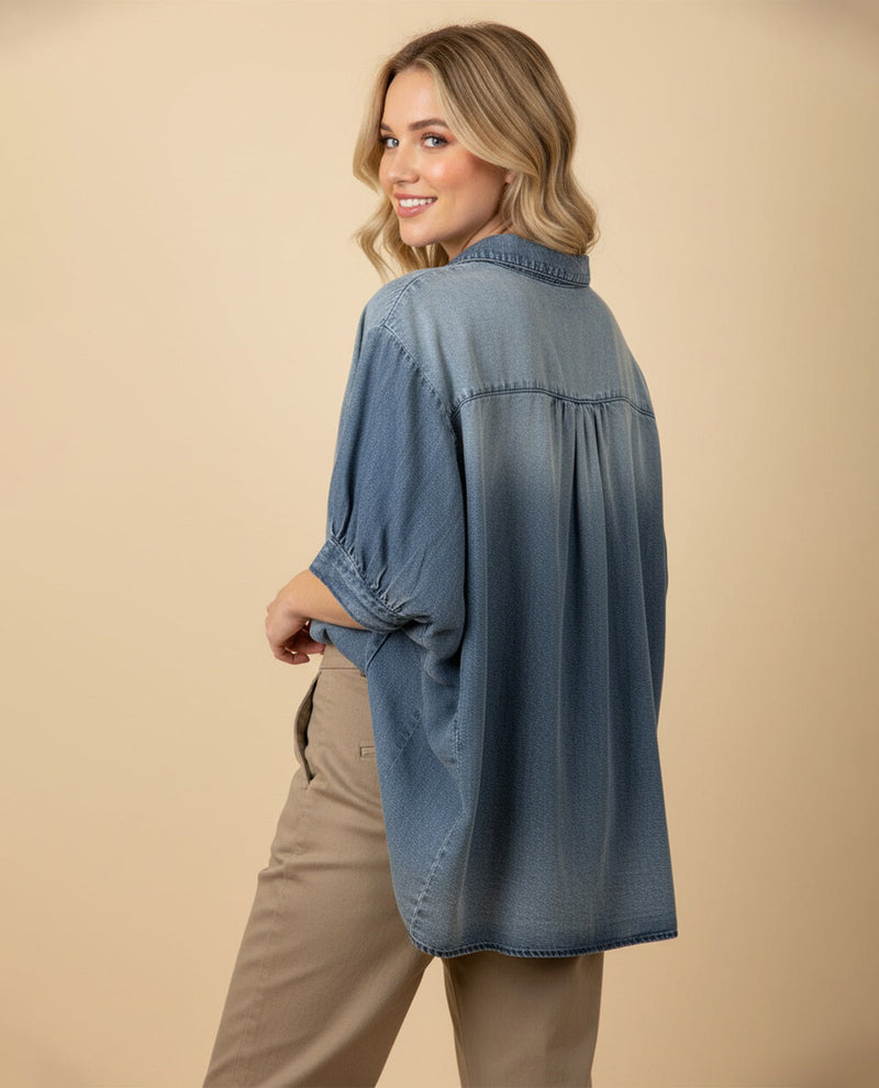 Woman wearing a blue denim shirt and beige pants on a beige background