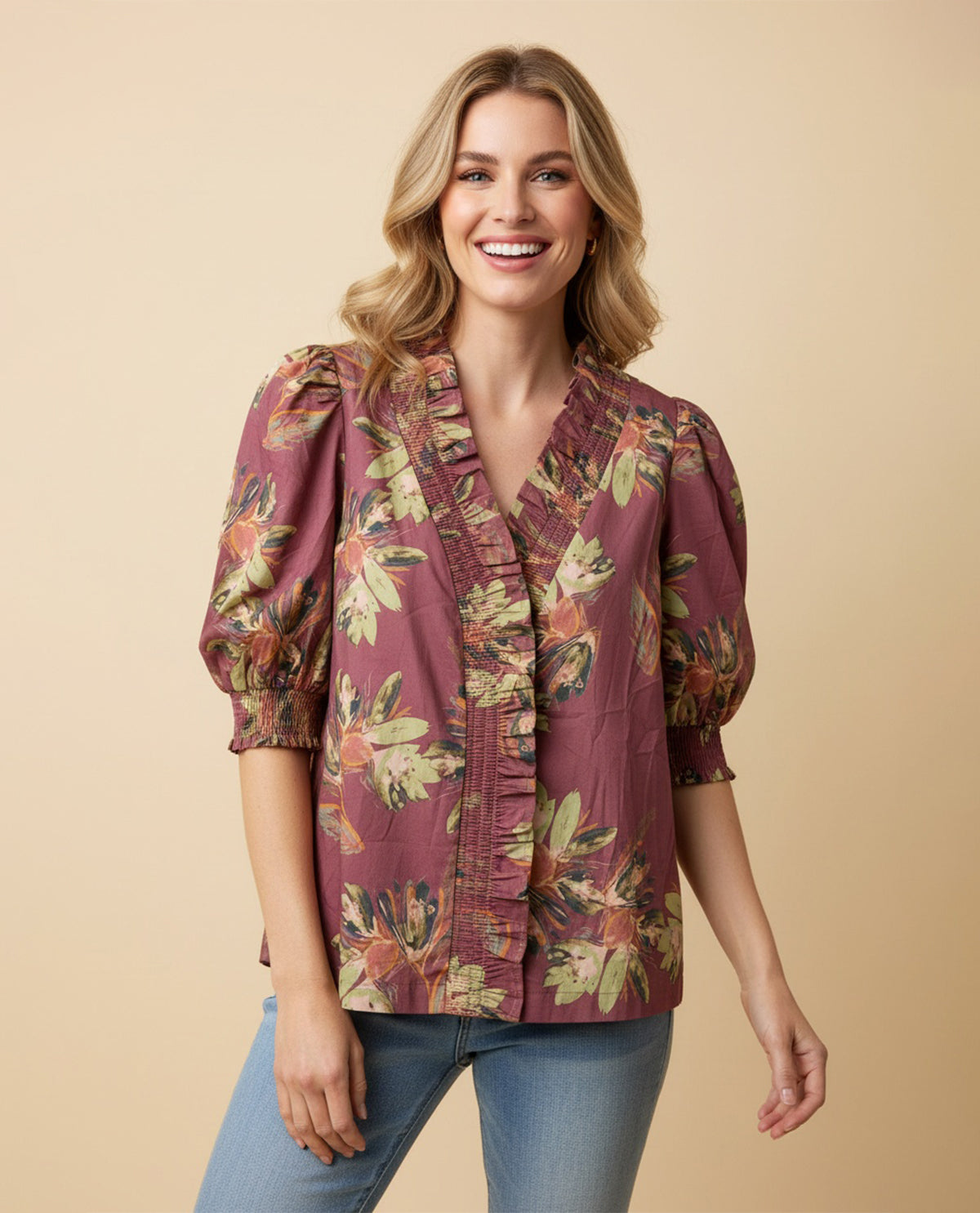 Woman wearing a floral blouse with puff sleeves on a beige background