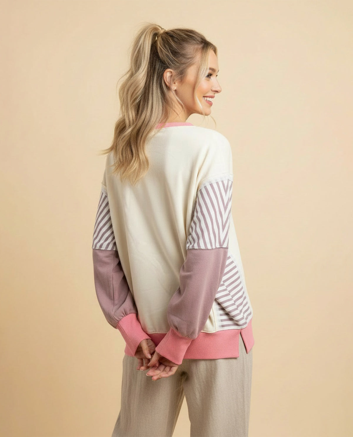 Woman wearing a color-blocked sweater with long sleeves on a beige background
