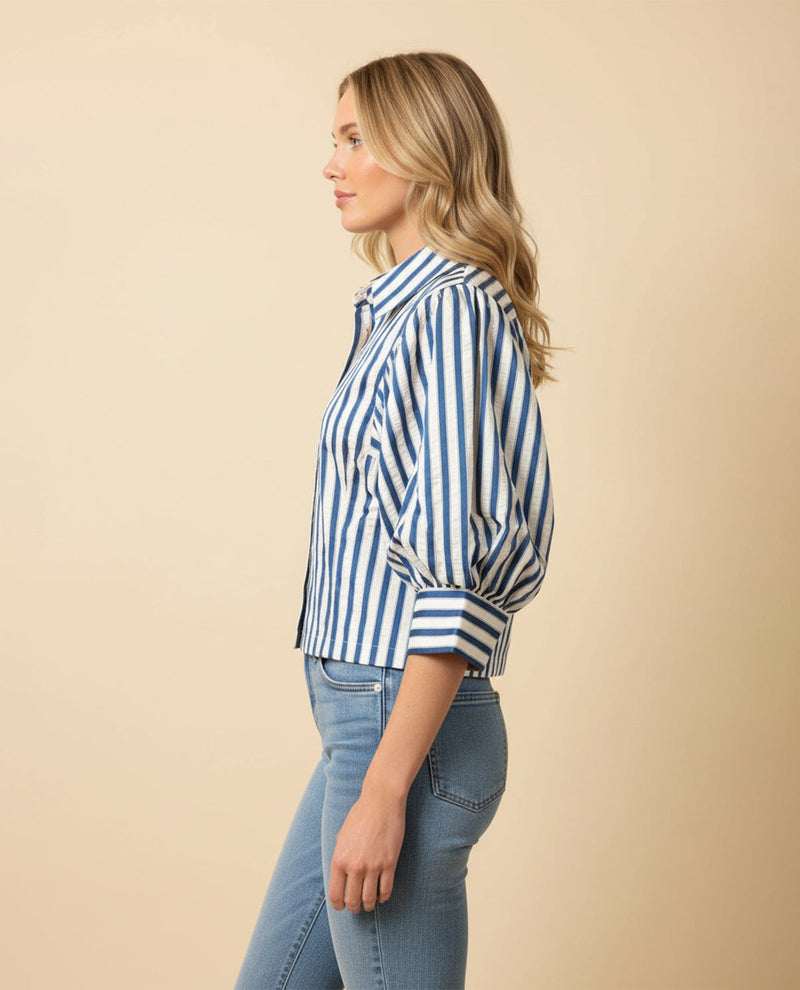 Woman wearing a blue and white striped shirt and jeans on a beige background