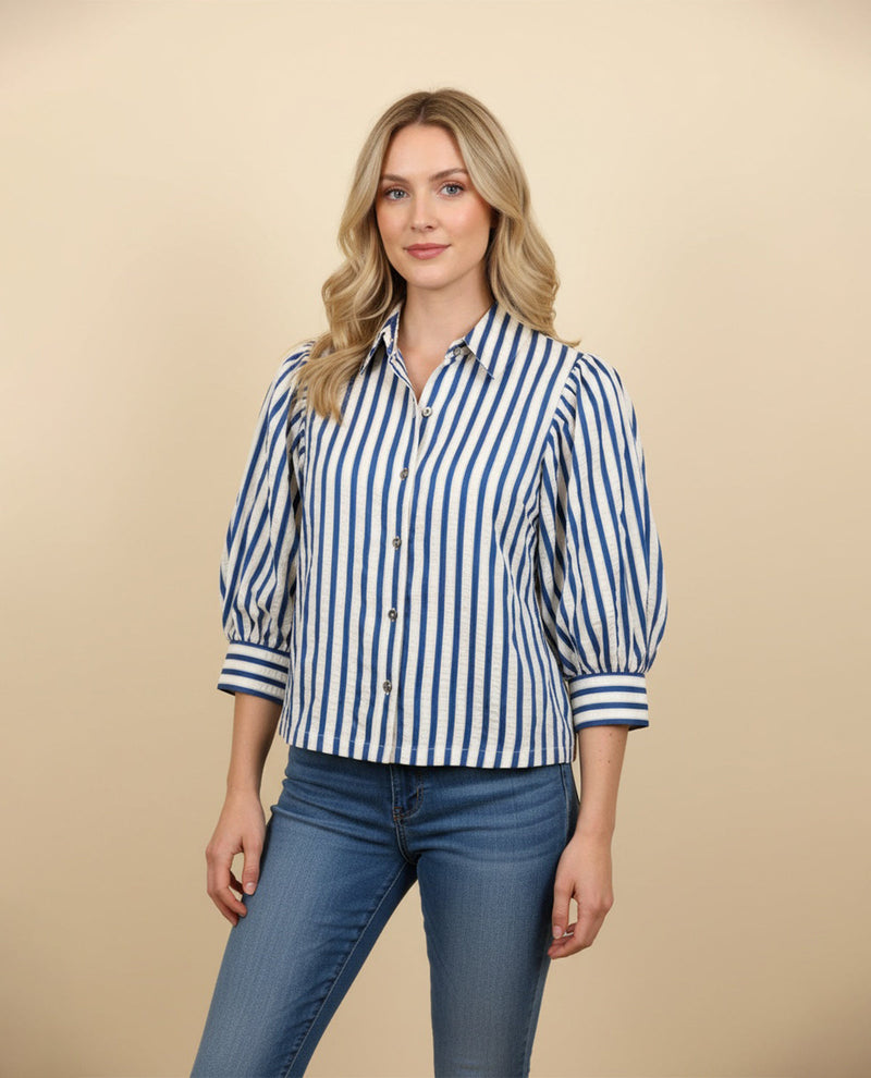 Woman wearing a blue and white striped shirt and jeans on a beige background
