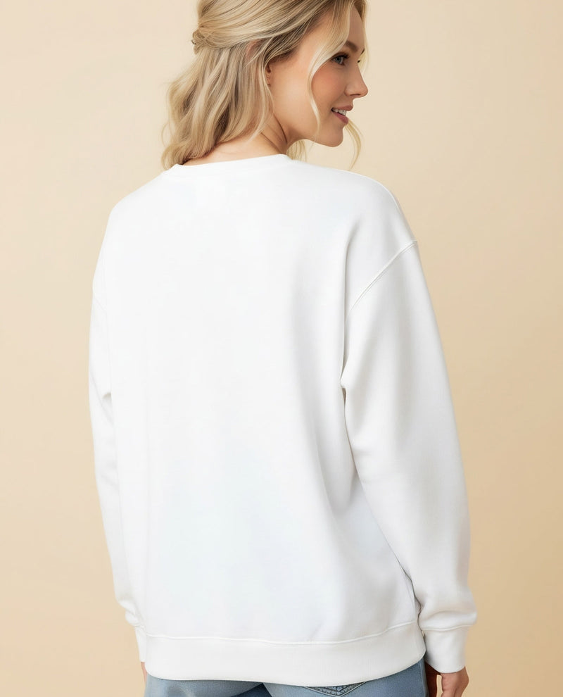 A woman shown from the back wearing a plain white crewneck sweatshirt, paired with light blue jeans, against a solid beige studio background.