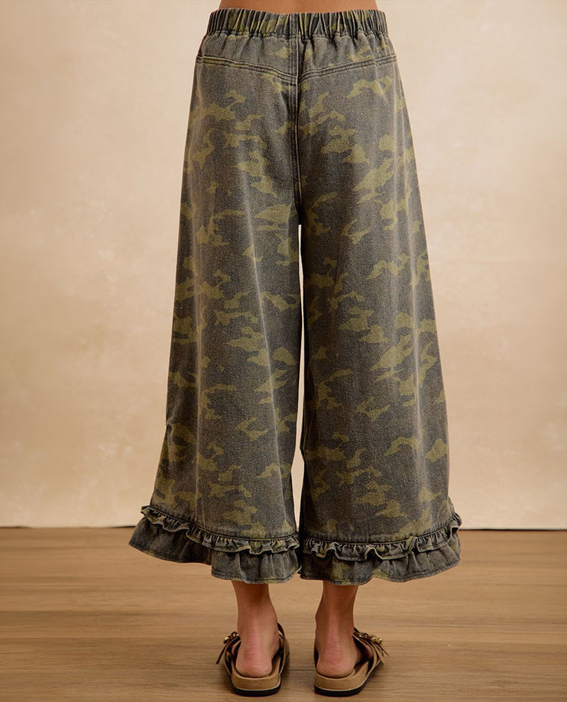 Camouflage-patterned pants with ruffled hem on a plain background