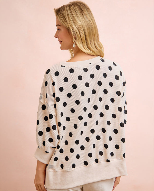 Woman wearing a polka dot blouse against a pink background