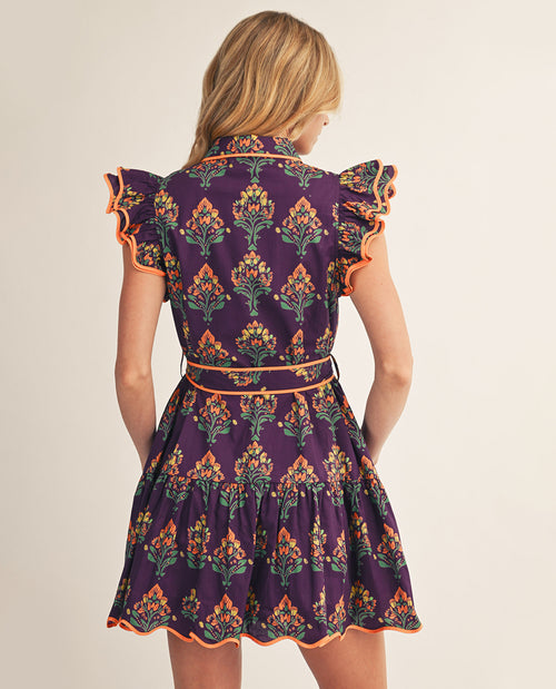 Woman wearing a purple floral dress with orange accents on a beige background