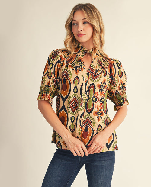 Woman wearing a patterned blouse with a neutral background