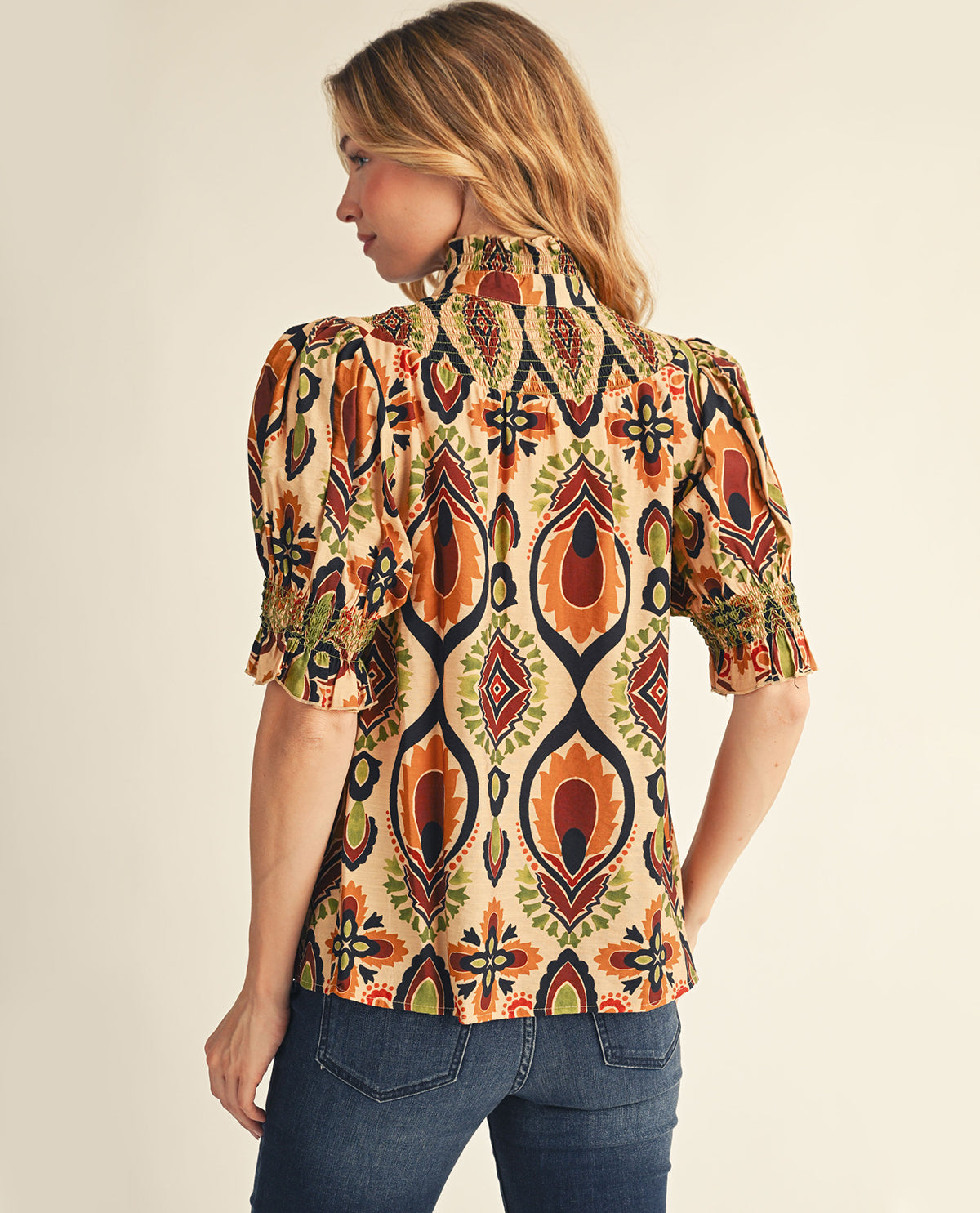 Woman wearing a patterned blouse with a neutral background
