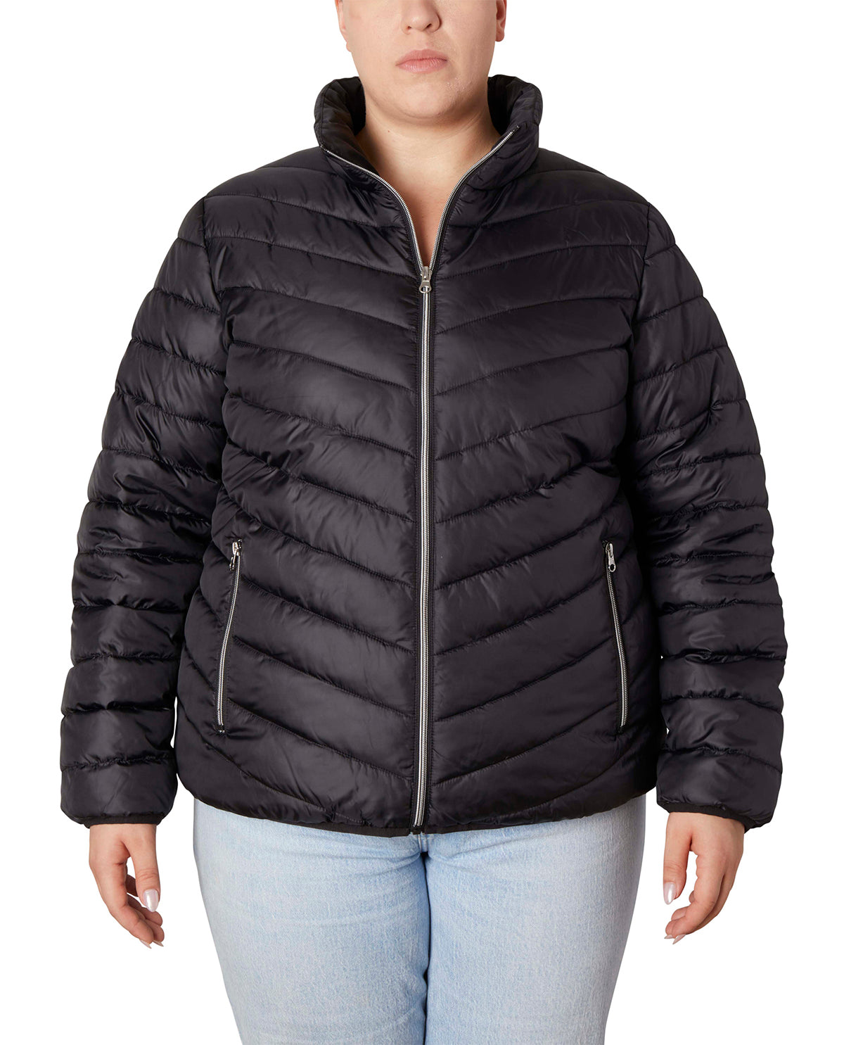 A woman wearing a black quilted puffer jacket with a stand-up collar and silver zipper details, paired with light blue jeans, against a plain white background.