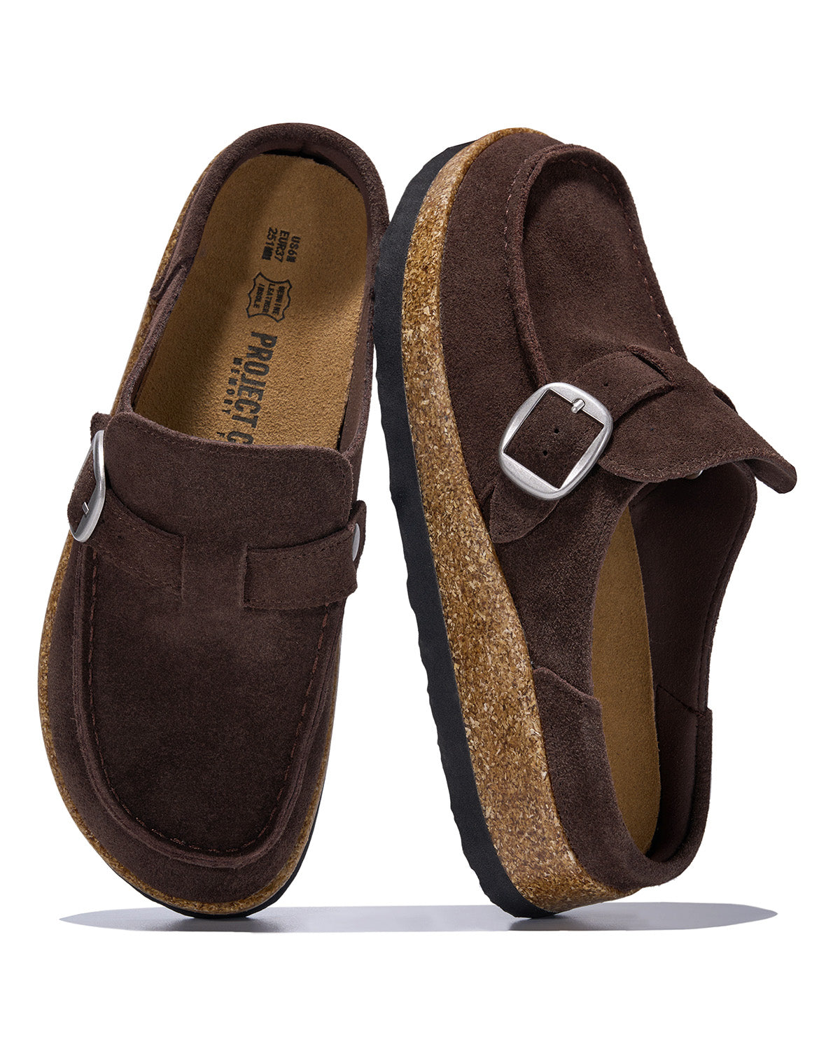 A pair of dark brown suede slip-on clogs with adjustable strap buckles, cork midsoles, and black outsoles, shown on a white background.