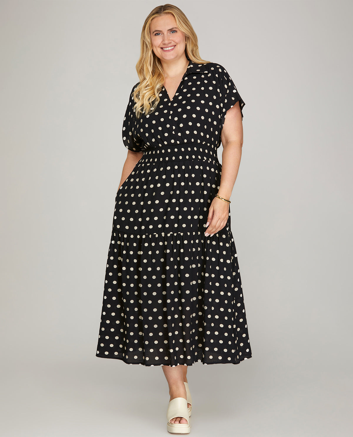 Woman wearing a black dress with white polka dots on a gray background