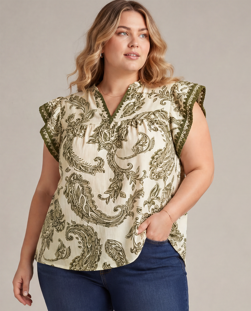 Woman wearing a patterned top with ruffled sleeves against a neutral background