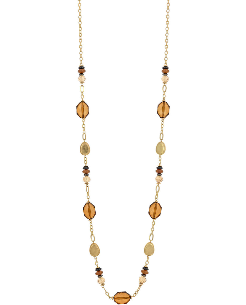 A gold-tone beaded necklace featuring faceted amber-brown glass beads, round cream beads, and small dark brown beads, displayed against a solid white background.