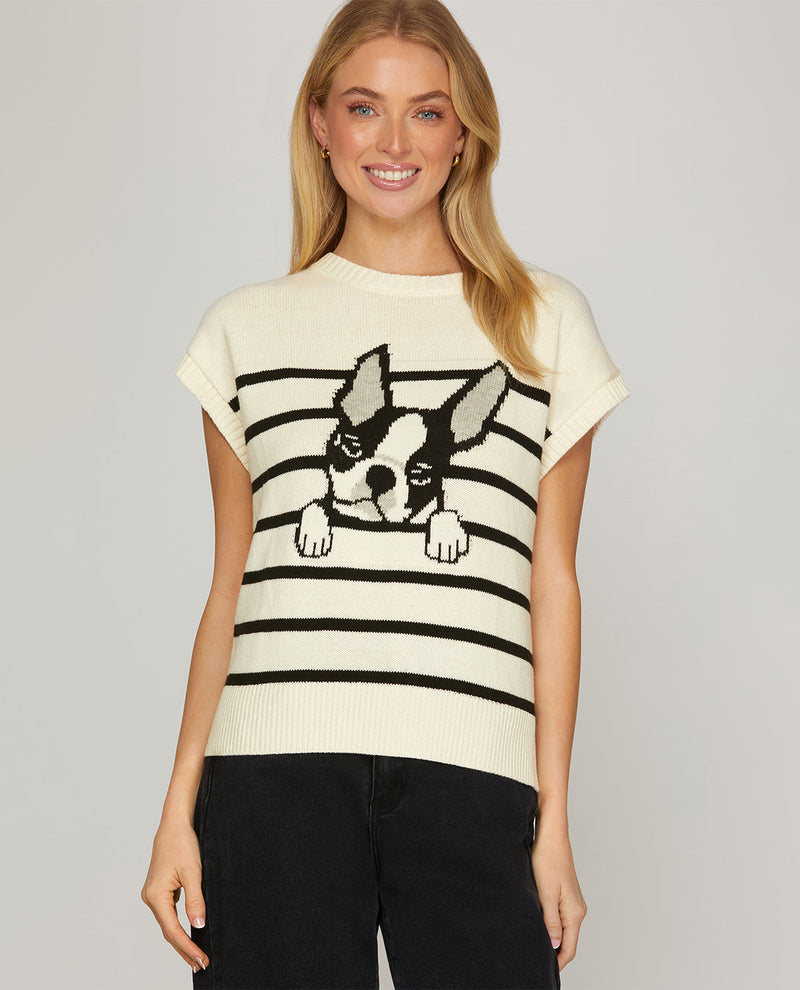 A woman wearing a cream short-sleeve knit sweater with black horizontal stripes and a black-and-white Boston Terrier graphic on the front, paired with black pants, against a light gray studio background.