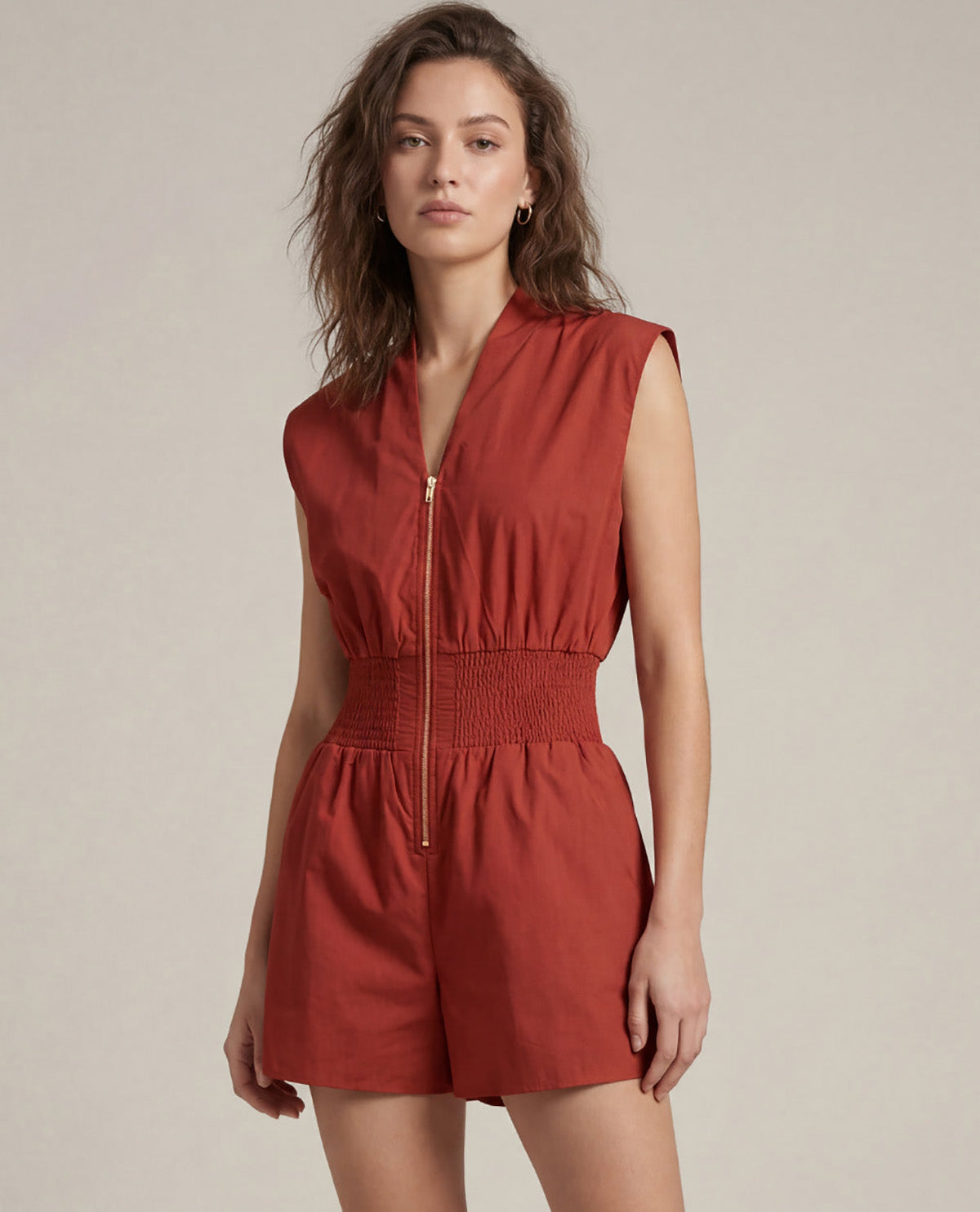 Woman wearing a red romper against a plain background