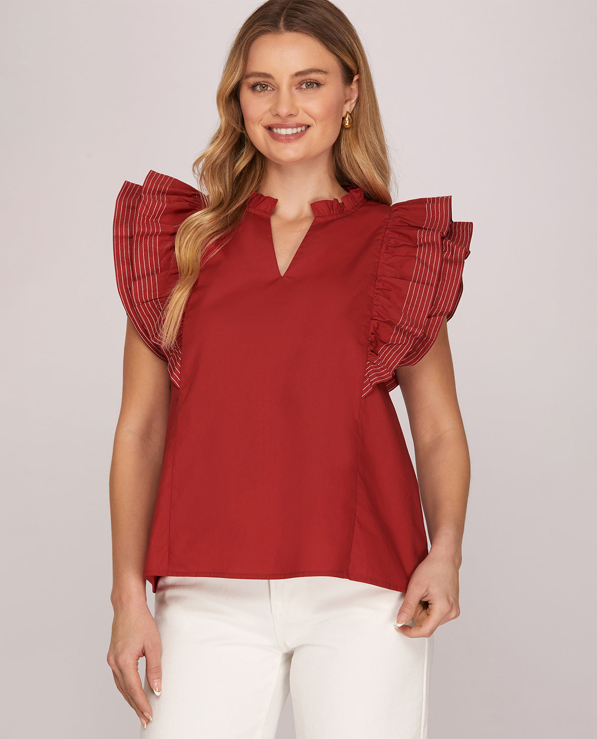 Woman wearing a red blouse with ruffled sleeves on a light background