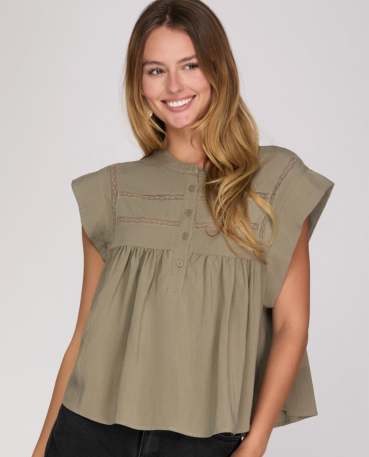 Woman wearing a green sleeveless top against a plain background