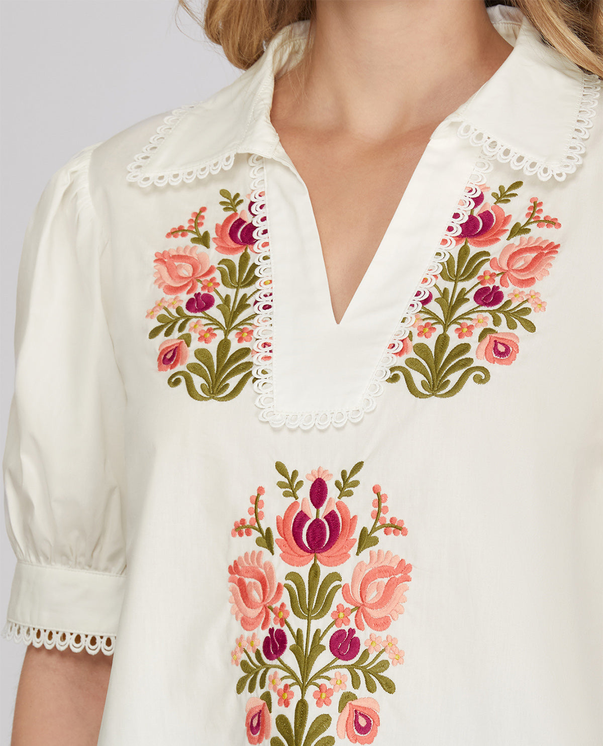 White blouse with floral embroidery on a plain background