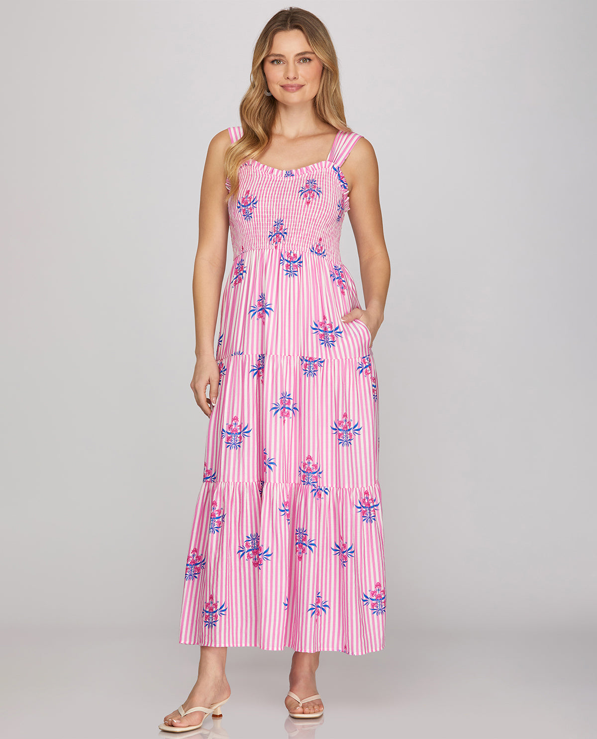 Woman wearing a pink dress with floral pattern on a plain background